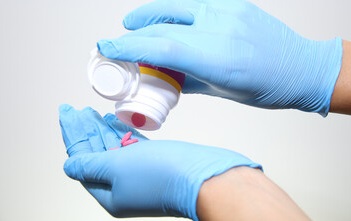 Medication aide holding 2 white pill medications and glass of water 