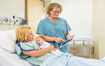 Nurse with postpartum mother and baby