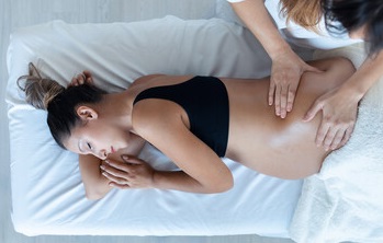 Pregnant woman lying on her side on the massage table. 