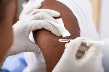 Healthcare professional administering insulin in a patient's arm.