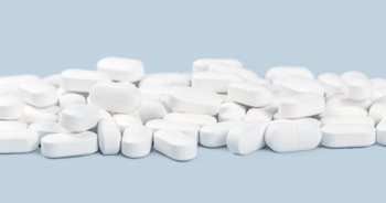large amount of white pills on a blue background