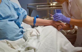 Nurse inserting an IV into a patient's forearm,