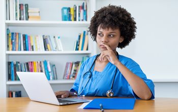 Nurse sitting at computer thinking