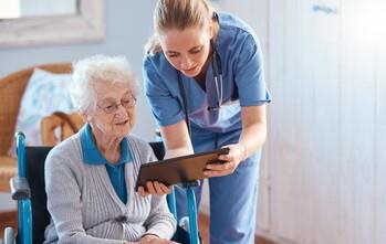 Nurse with elderly patient reviewing chart.