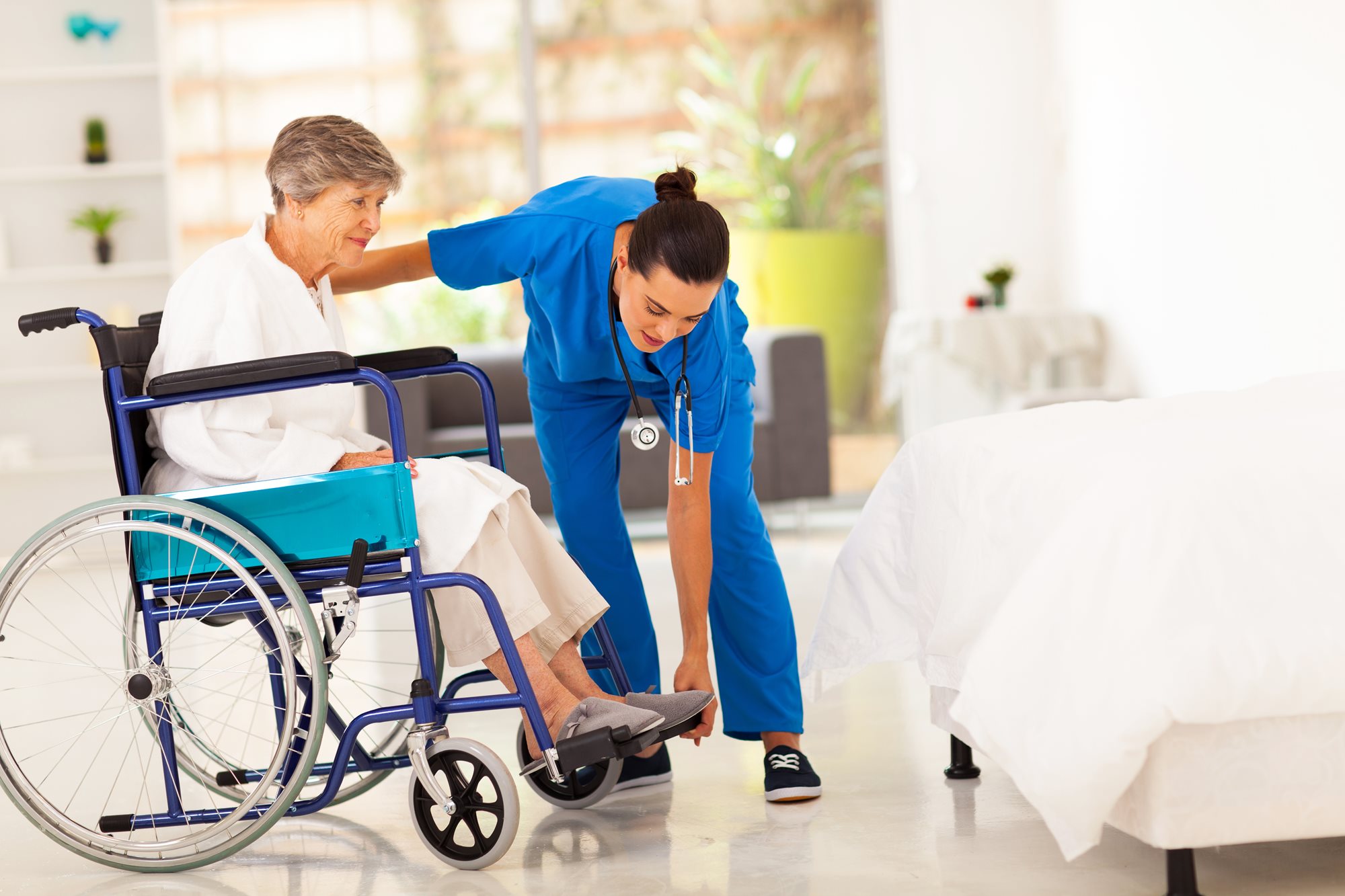 nurse assistant helping a woman in a wheelchair