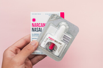 Box of narcan nasal spray on a pink background