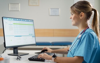Nurse reviewing patient medications on a computer screen.