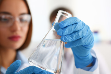 Chemist in lab holding beaker.