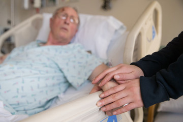 Elderly man in a hospital bed with hospital gown on.