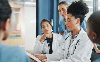 Nurse reviewing patient medication records with other staff members.
