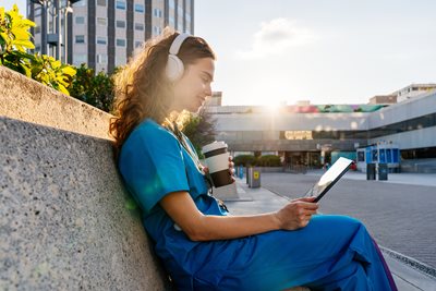 Nurse listening to CE course on tablet with coffee
