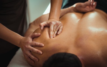 massage therapist performing massage to a shoulder.