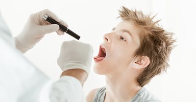 looking into a boy' throat with a flashlight