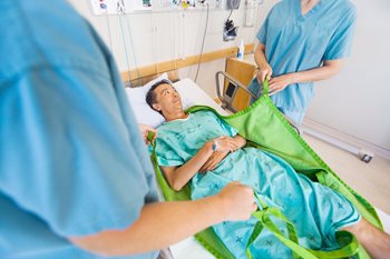 Nurses using transfer aid to safely turn and lift patient