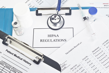 Medical paperwork on a clip board with HIPAA written across it. 