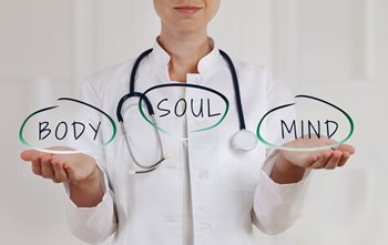 healthcare professional in white holding animated signs of body, soul, mind