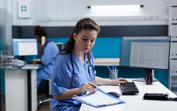 Nurse reviewing patient medications on a computer screen.