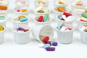 Medication cups with brightly colored capsules and pills. 