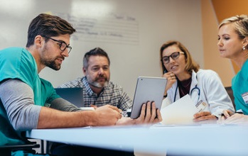 Patient care team, 4 staff members sitting around a table, observing patient records