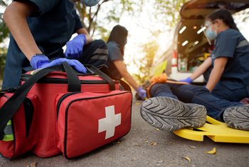 EMT/Paramedics wearing gloves and a face shield helping a patient