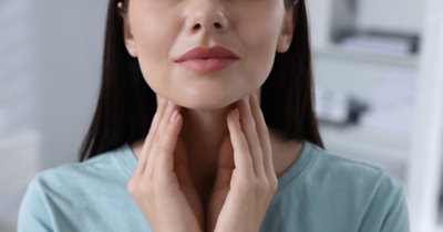 woman holding hand over neck