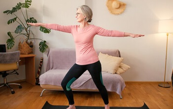 older woman in a pilates pose with outstretched arms. 