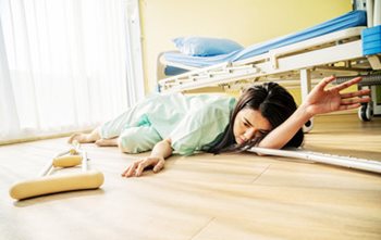 Patient lying on the hospital room floor with crutches lying on the floor, as if she fell. 