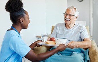 Nurse handing resident a lunch tray