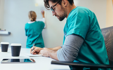 nurse in scrubs charting at a desk
