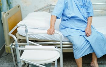 Patient in a blue hospital gown, sitting on the side of the bed.